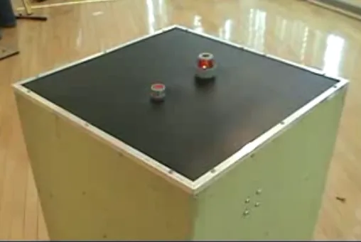 A red button and small indicator light on the dark top of Suspect Device