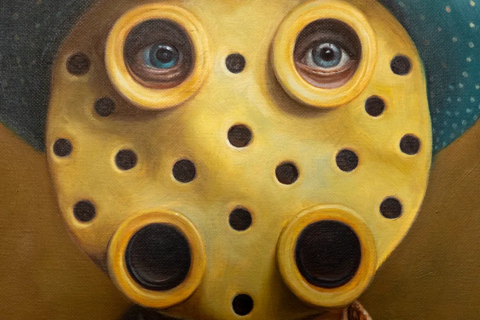 Close-up of the portrait face with round holes and eyes set into a yellow surface.