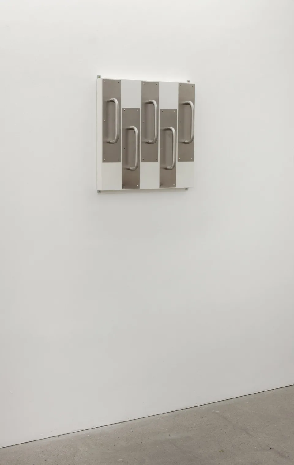 A wall-mounted arrangement of metal door handles