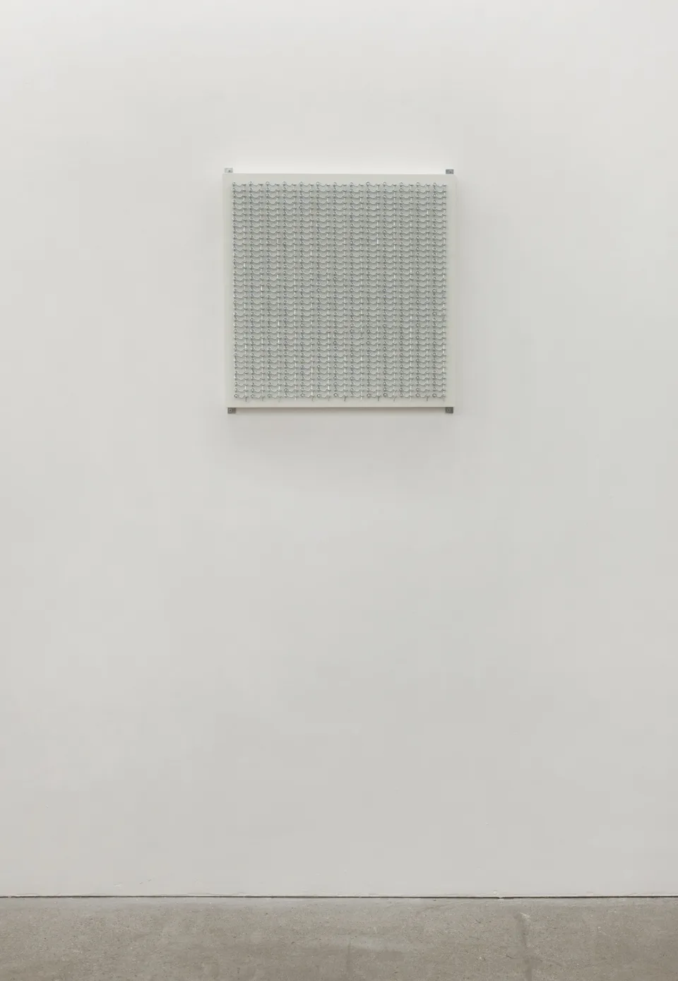 A small grid of metal hooks installed on a large white wall
