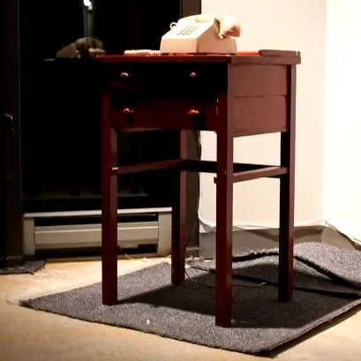 A cream telephone resting on a small wooden table in the Pavlov installation