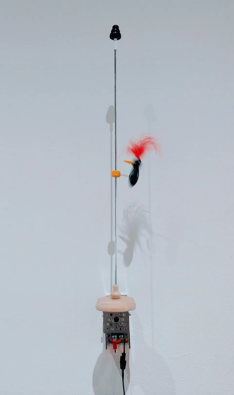 A long rod and small colorful toy mounted above a Toybots mechanism
