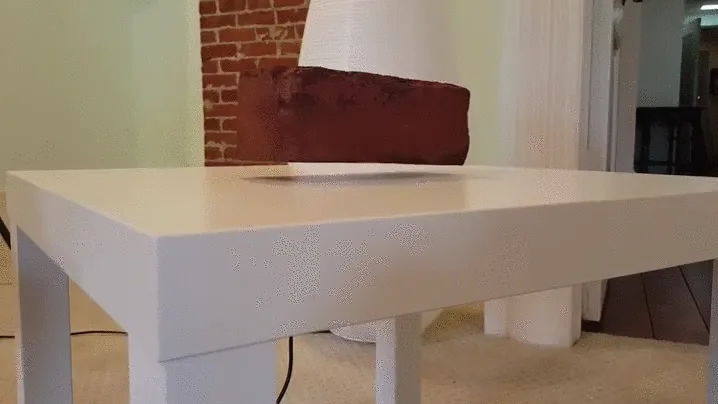 A red brick floats and turns above a white table
