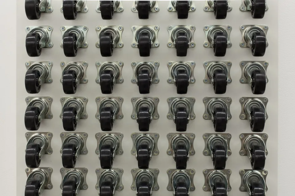 Close view of rows of black caster wheels and their metal brackets