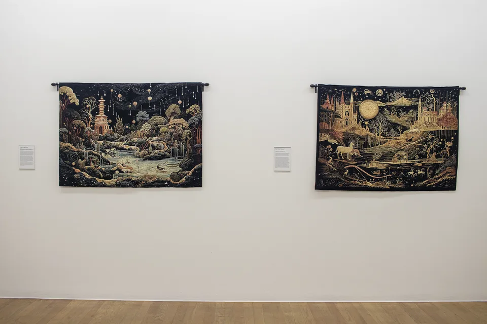 Two dark woven landscapes hang on adjacent white walls: a pagoda and water on the left, castles and a golden orb on the right.