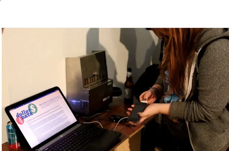 A participant connects a phone beside a laptop and the dollar$4DATA machine