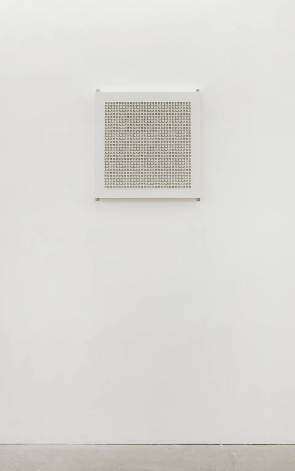 A dense grid of metallic domes installed on a white gallery wall