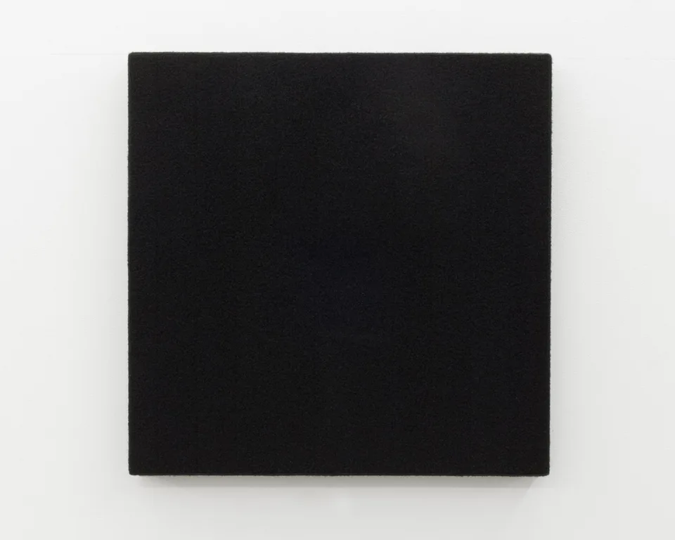 A black square panel with a fine textured surface