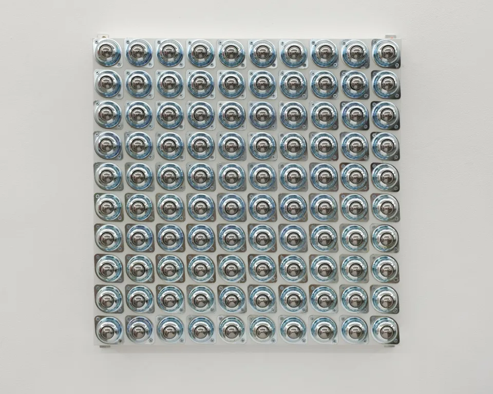 Circular metal fittings arranged in a grid on a white panel