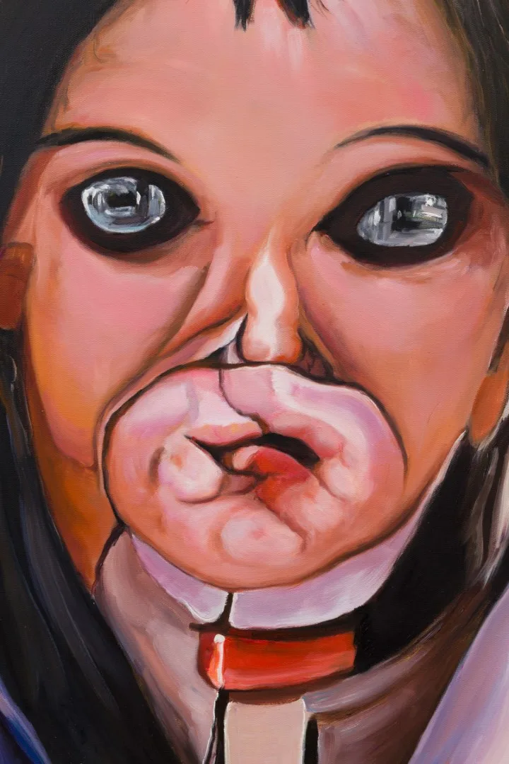 Detail of a painted face with large reflective eyes and layered pink mouth-like shapes.