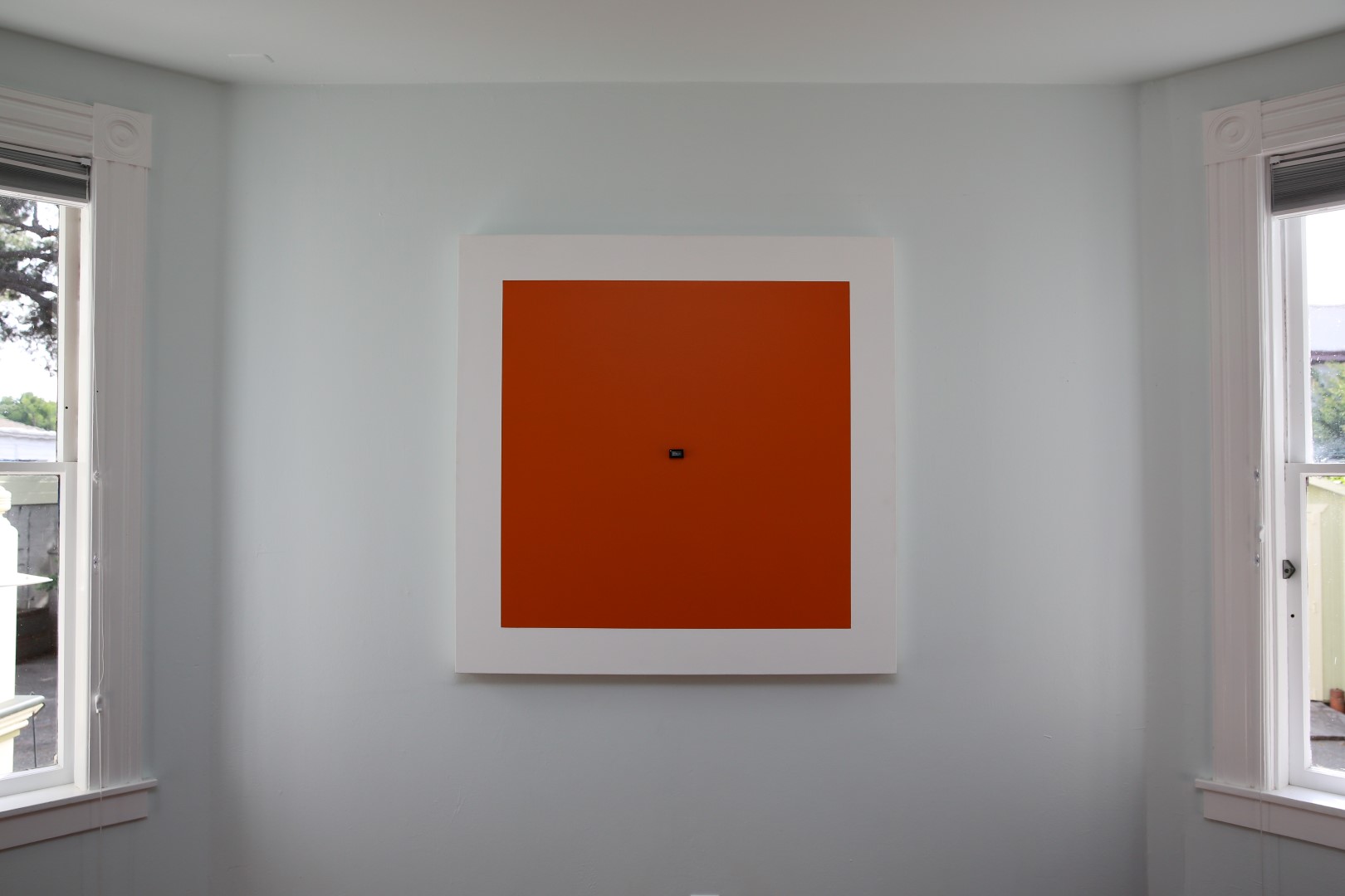 Square white canvas with a large orange square at its center and a small radar sensor embedded in the middle